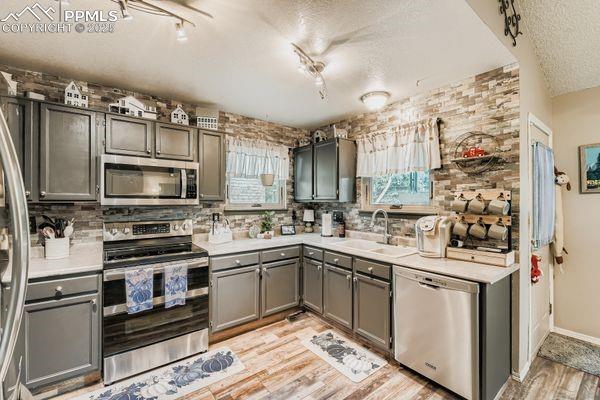 Image 5 of 15: Kitchen with stainless steel appliances, light countertops, light wood fini