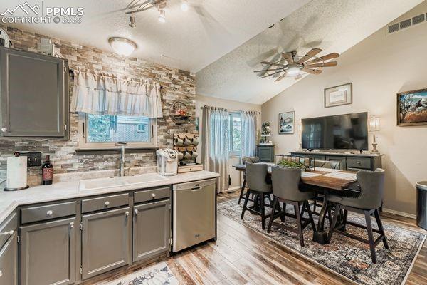 Image 6 of 15: Kitchen with gray cabinets, lofted ceiling, light countertops, light wood-s