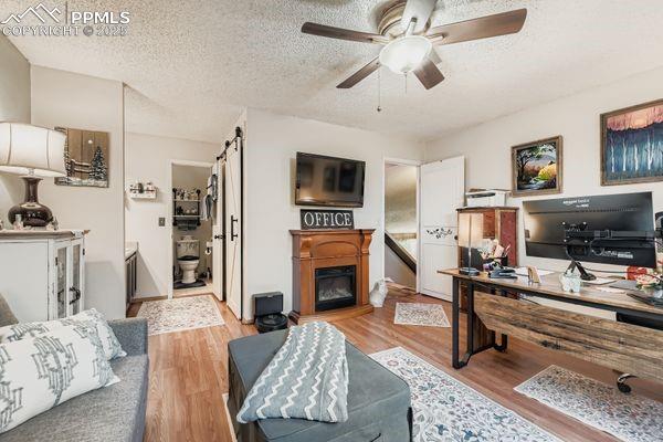Image 9 of 15: Office with light wood finished floors, a textured ceiling, a ceiling fan,