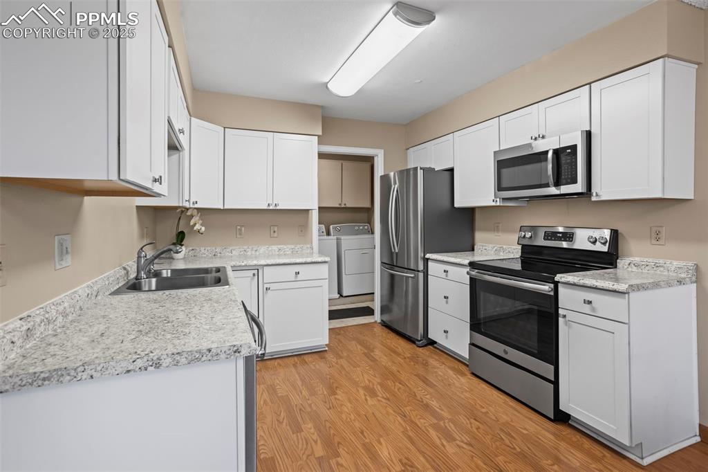 Image 3 of 17: Kitchen with stainless steel appliances, a sink, washing machine and dryer,