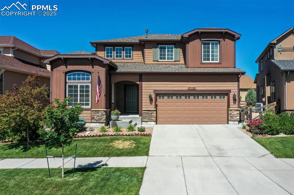 Image 46 of 46: View of front of home with a garage, driveway, stone siding, a front yard,