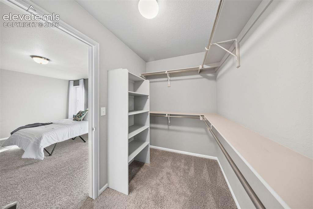 Image 22 of 48: The primary closet has wooden shelves with lots of built-ins. Bring on the