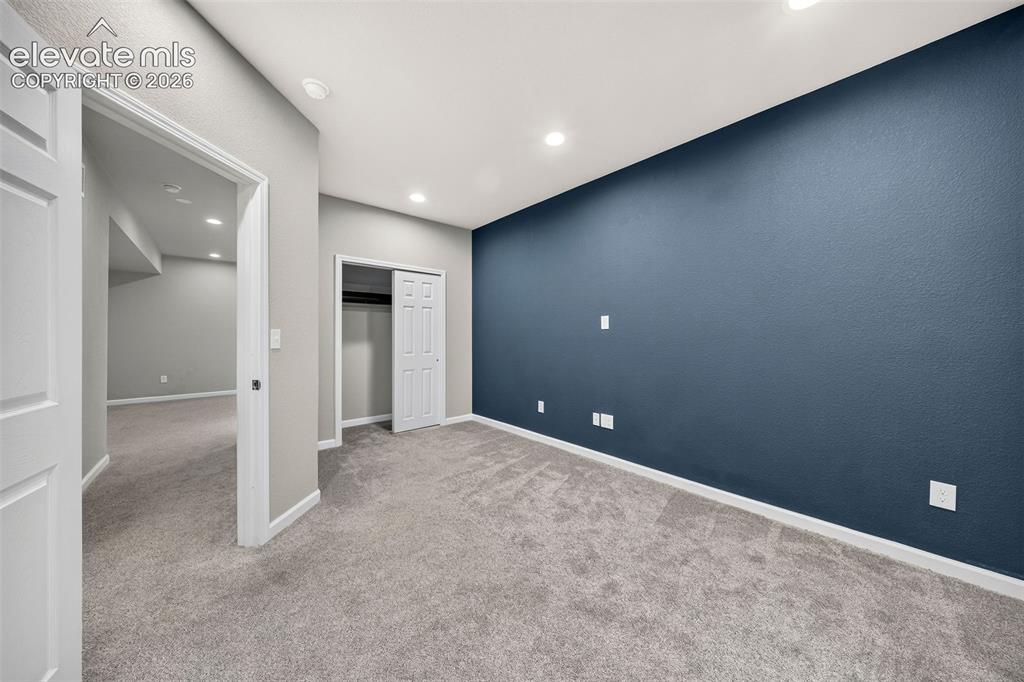 Image 32 of 48: The basement-level bedroom has a blue accent wall and a double reach-in clo