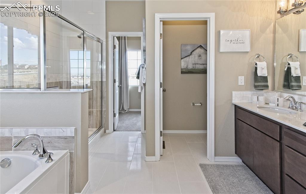 Image 24 of 30: Full bathroom with vanity, a stall shower, a garden tub, and light tile pat