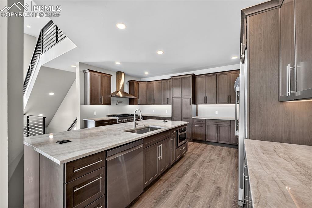 Image 10 of 50: Kitchen with light stone counters, dishwasher, light wood-style floors, wal