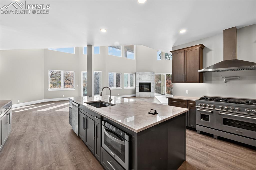 Image 11 of 50: Kitchen featuring open floor plan, wall chimney range hood, stainless steel