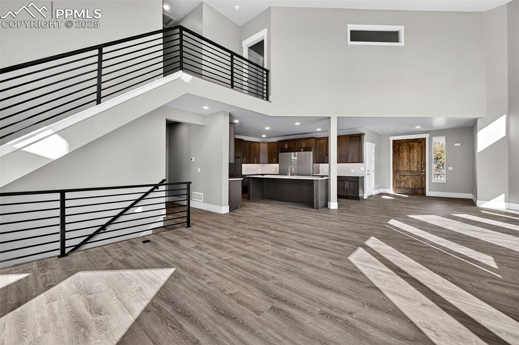 Image 14 of 50: Unfurnished living room with a towering ceiling and light wood-style floors