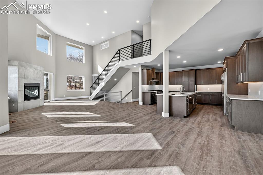 Image 8 of 50: Unfurnished living room featuring a high ceiling, stairway, a tiled firepla