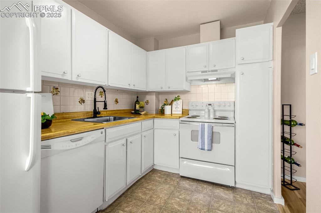 Image 6 of 14: White cabinets and tile backsplash