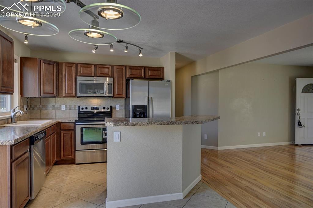 Image 10 of 33: Kitchen featuring appliances with stainless steel finishes, backsplash, a k