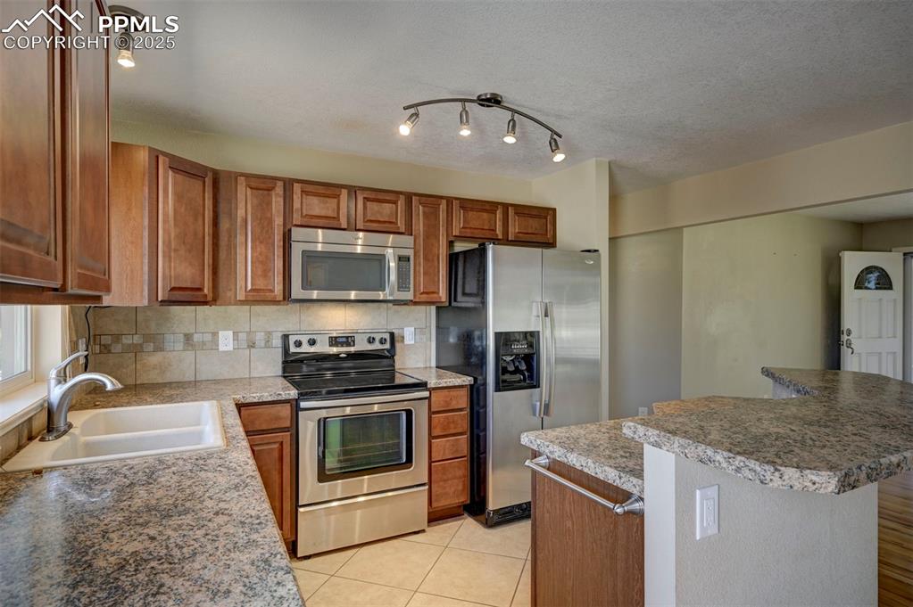 Image 11 of 33: Kitchen featuring appliances with stainless steel finishes, brown cabinets,