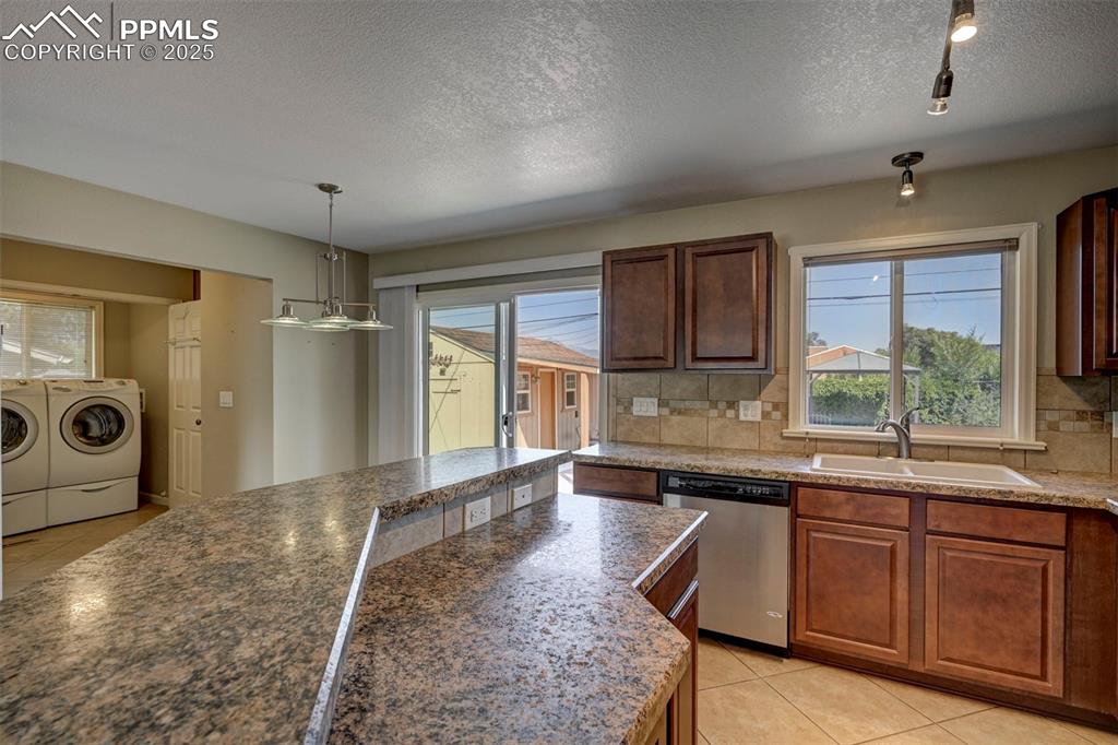 Image 12 of 33: Kitchen featuring independent washer and dryer, light tile patterned floors