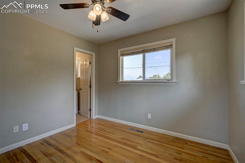 Image 18 of 33: Empty room with light wood finished floors and a ceiling fan