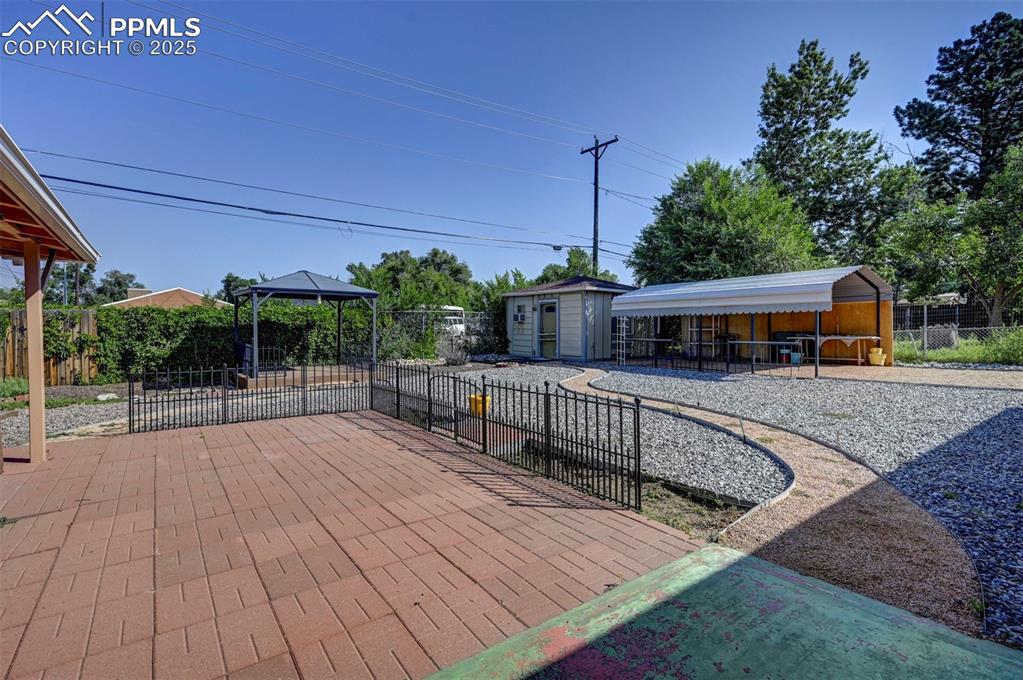 Image 28 of 33: View of patio featuring a gazebo, a storage unit, and grilling area