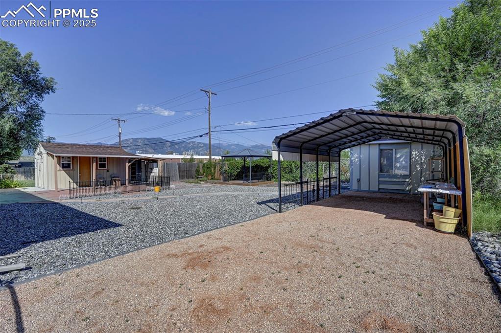 Image 29 of 33: View of yard with a detached carport, driveway, and covered porch