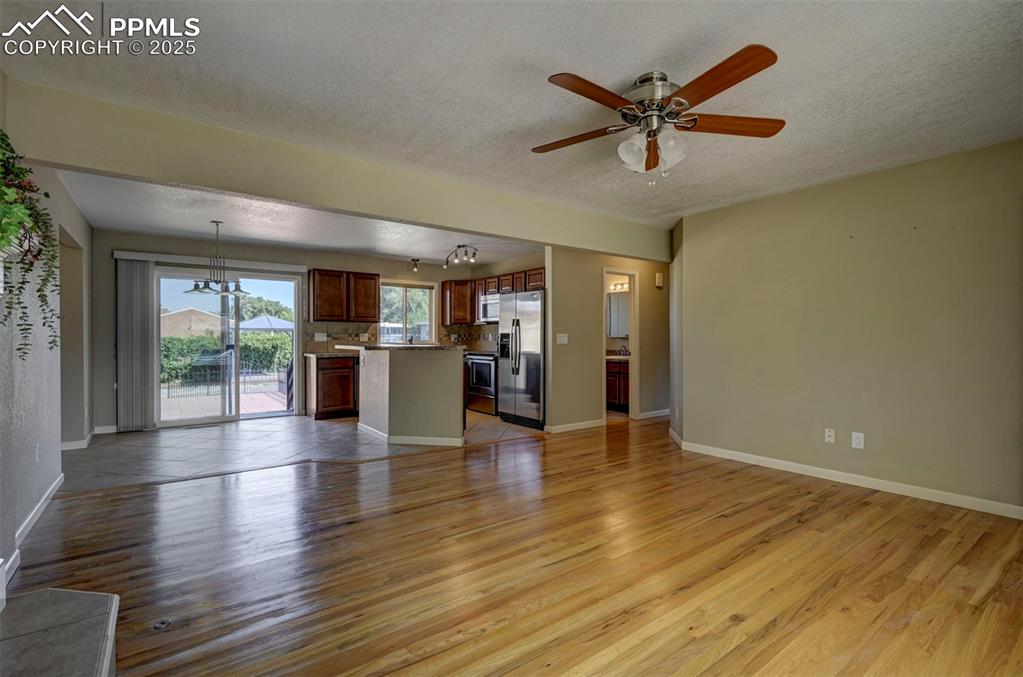 Image 6 of 33: Unfurnished living room with light wood-style floors, a textured ceiling, c