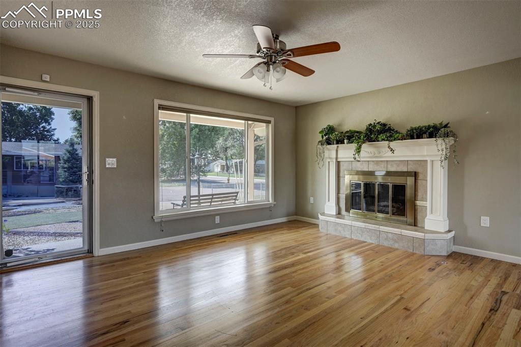 Image 7 of 33: Unfurnished living room with wood finished floors, a textured ceiling, a ce