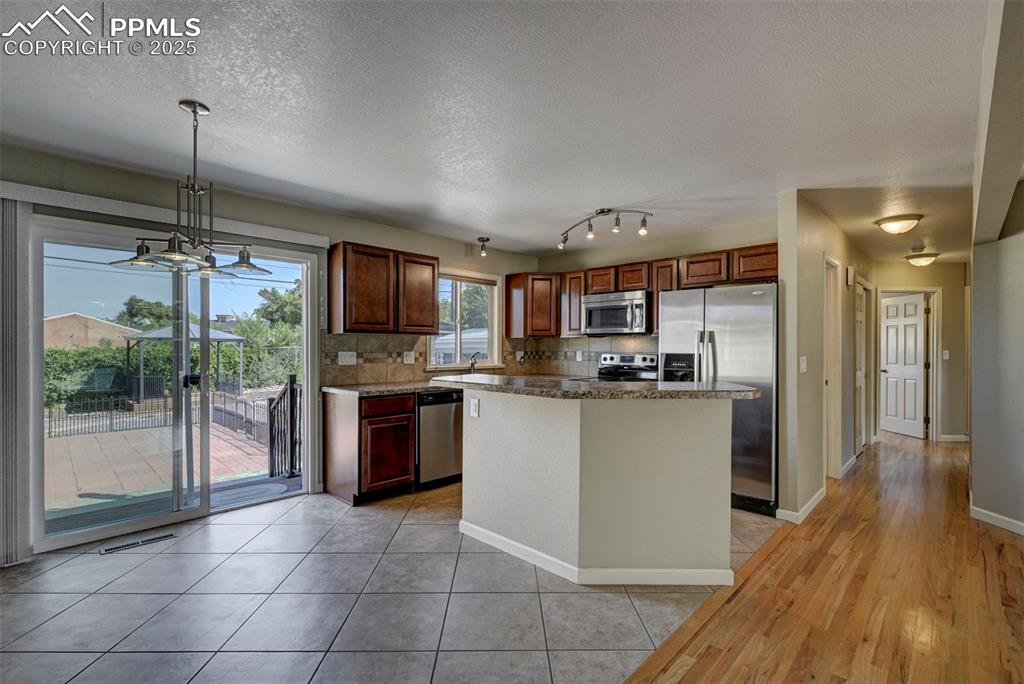 Image 9 of 33: Kitchen featuring decorative backsplash, appliances with stainless steel fi