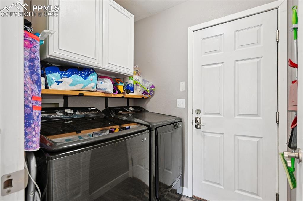 Image 15 of 29: Washroom featuring separate washer and dryer, cabinet space, and wood finis