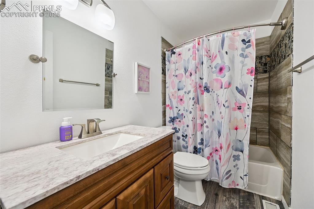 Image 24 of 29: Full bath with wood finished floors, vanity, and shower / tub combo with cu