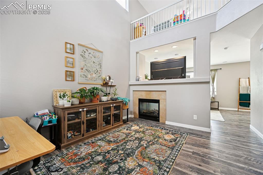 Image 7 of 29: Living area featuring a towering ceiling, wood finished floors, and a tile 