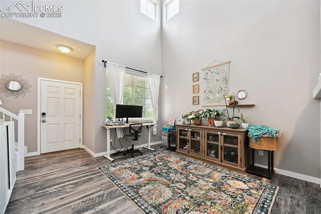 Image 8 of 29: Office with a towering ceiling and wood finished floors
