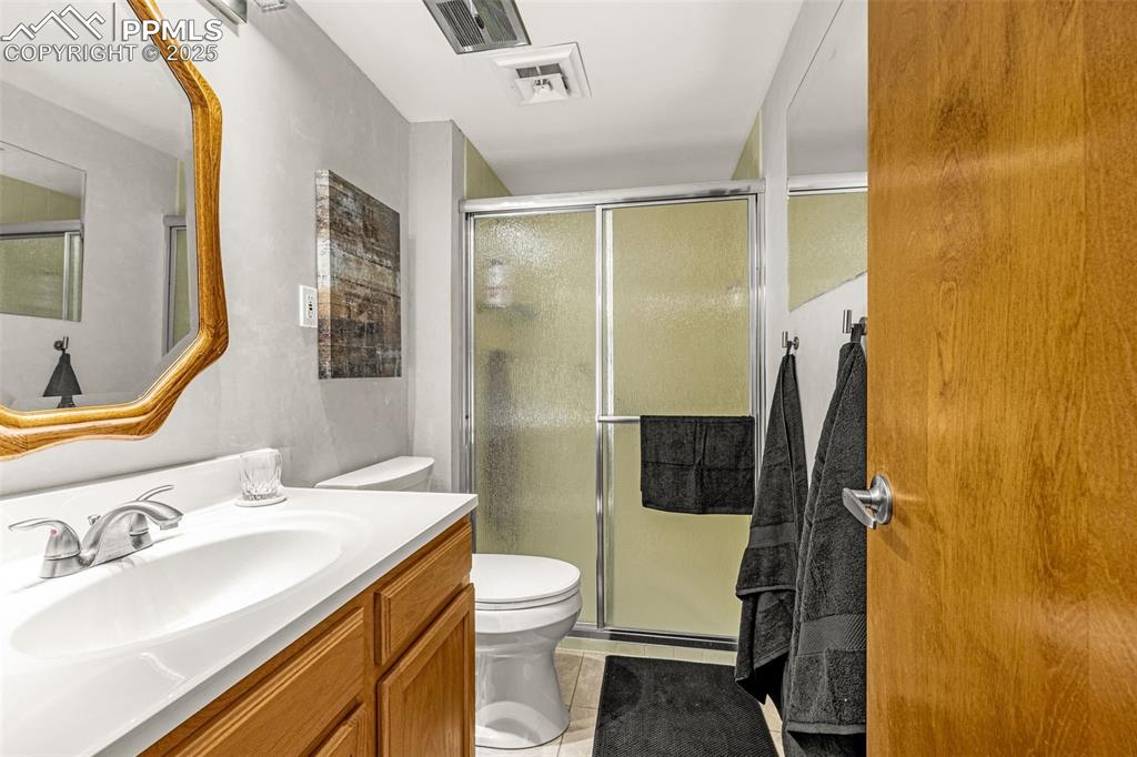 Image 15 of 24: Ensuite primary bedroom includes walk-in shower, newer vanity and tile floo