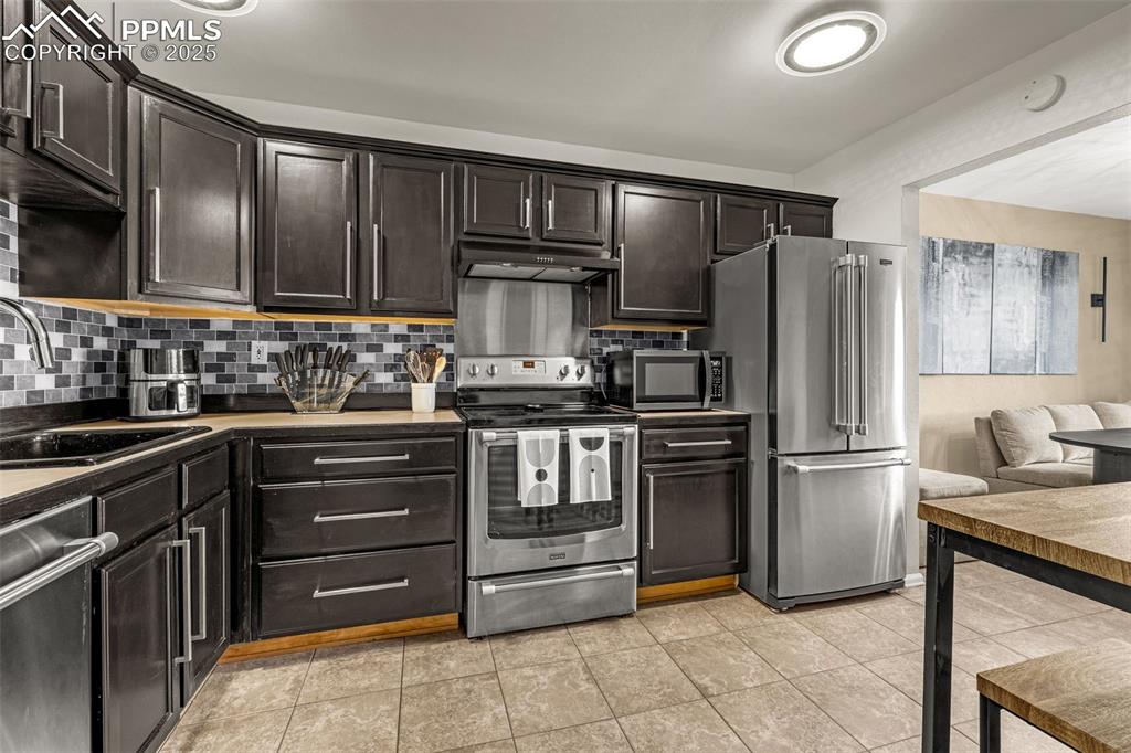 Image 7 of 24: Updated kitchen with stainless steel appliances, tile backsplash and update