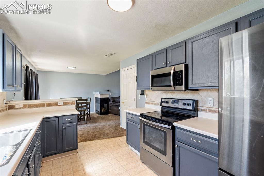 Image 8 of 28: Kitchen with decorative backsplash, light carpet, light countertops, a sink