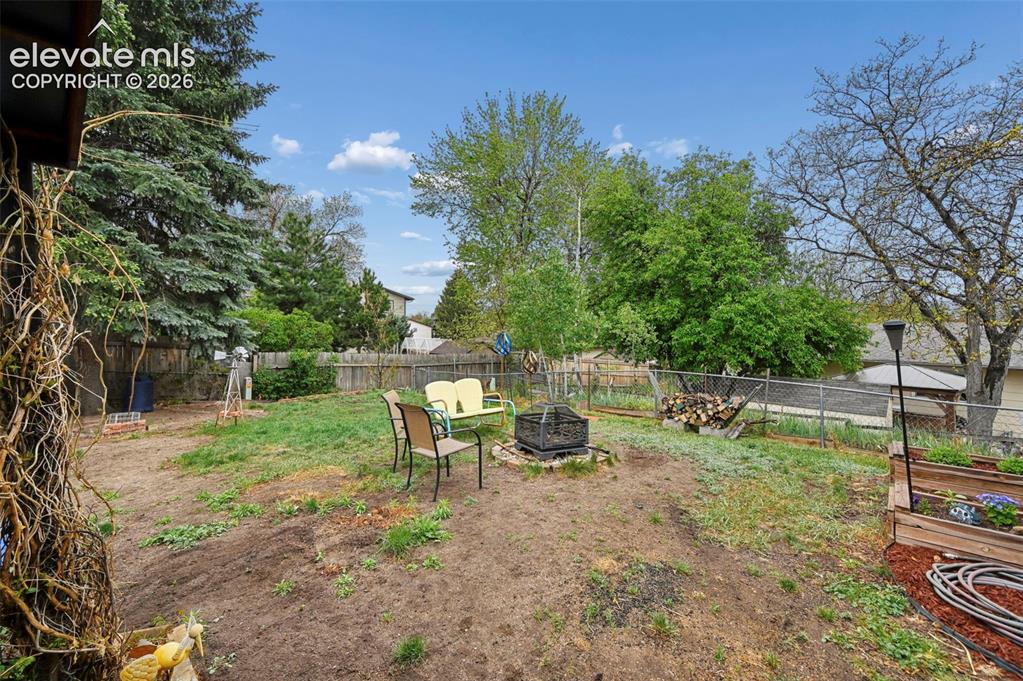 Image 30 of 33: Expansive outdoor space featuring a fire pit, mature trees, wood fencing, a