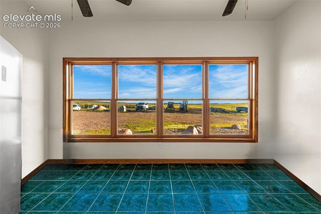 Image 17 of 50: Large window with wood trim, ceramic tile flooring, and ceiling fans