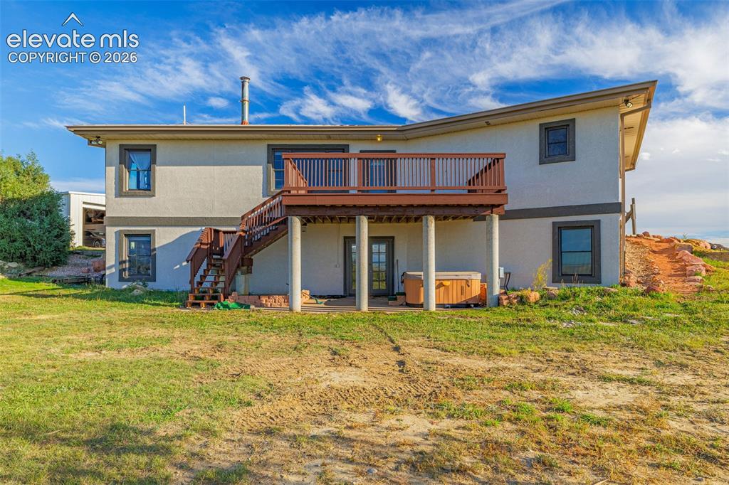 Image 2 of 50: Rear elevation with a multi-level deck featuring wood railings, a lower-lev