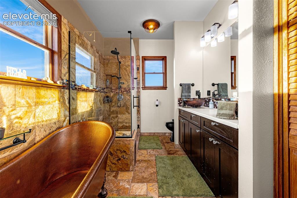 Image 21 of 50: Freestanding copper bathtub, walk-in shower with glass enclosure, dual vani