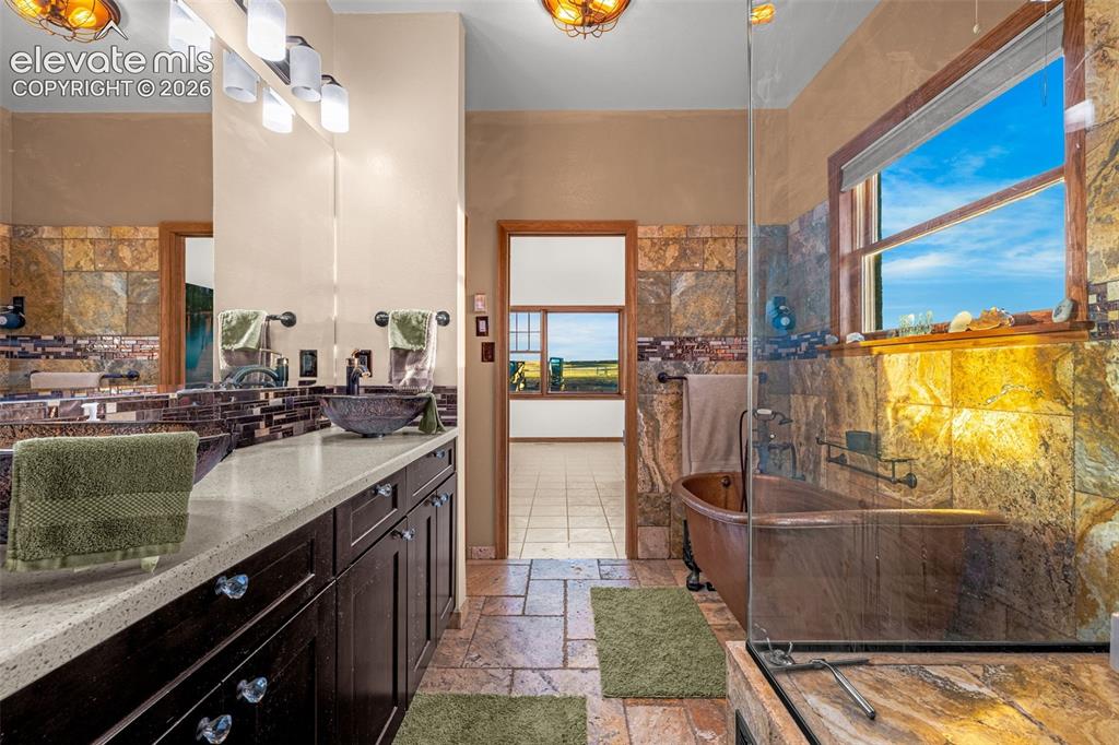 Image 23 of 50: Dual vanity with vessel sinks, stone countertops, and dark wood cabinetry