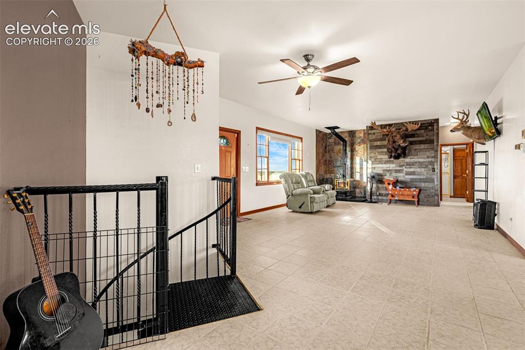 Image 27 of 50: Spacious room featuring light-toned tile flooring, a wood-burning stove wit