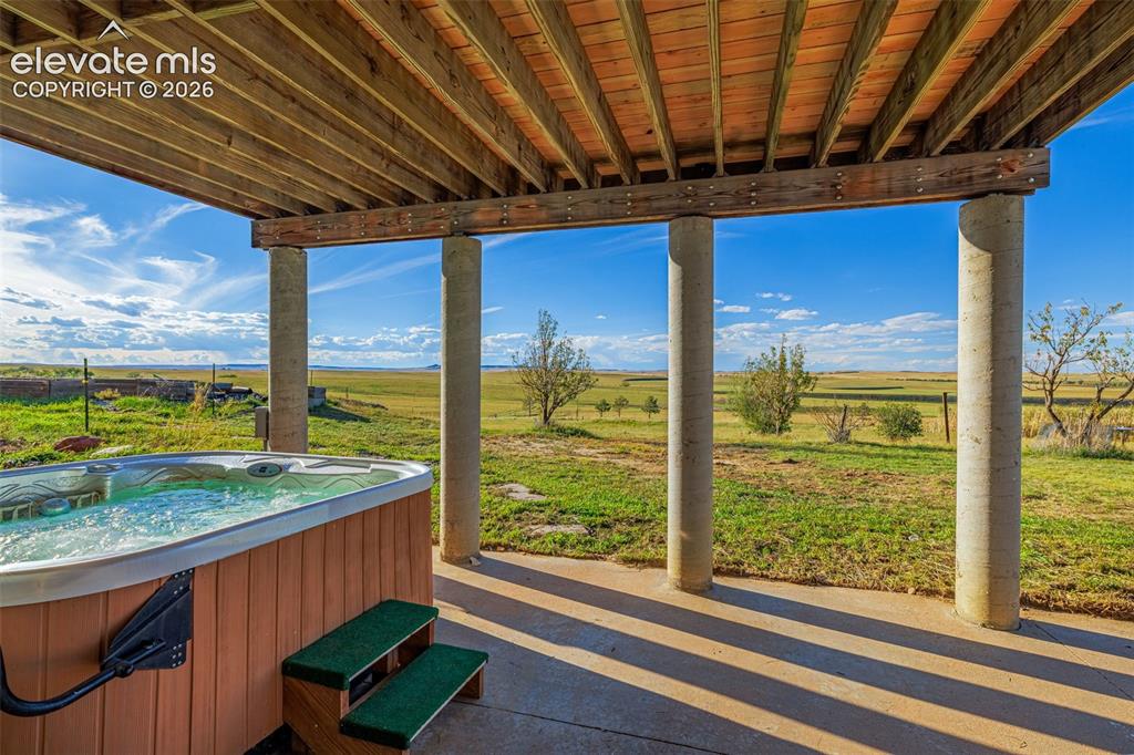Image 3 of 50: Covered patio featuring an integrated hot tub and concrete flooring, suppor