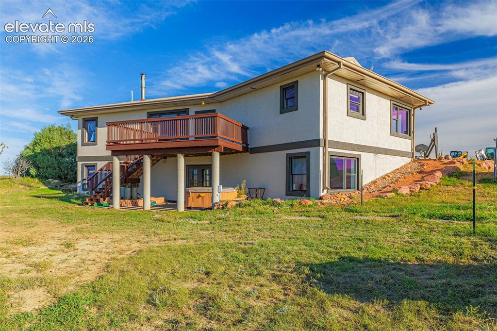 Image 41 of 50: Multi-level exterior with stucco finish, elevated wood deck with railings, 