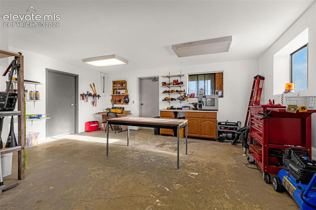 Image 46 of 50: Spacious utility room with concrete flooring, multiple windows, built-in ca