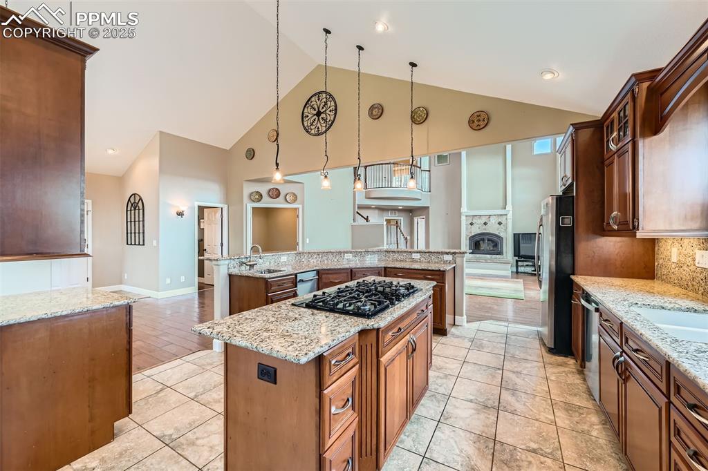 Image 10 of 27: Kitchen with a large island with sink, high vaulted ceiling, decorative bac