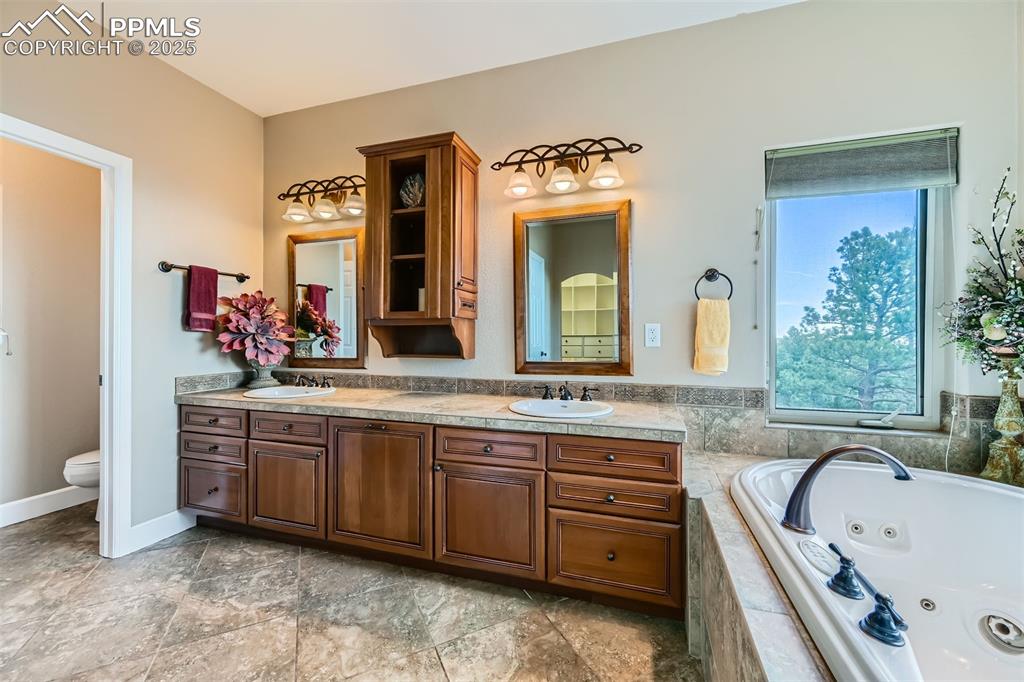 Image 16 of 27: 5 piece master bathroom featuring double vanity and a whirlpool tub