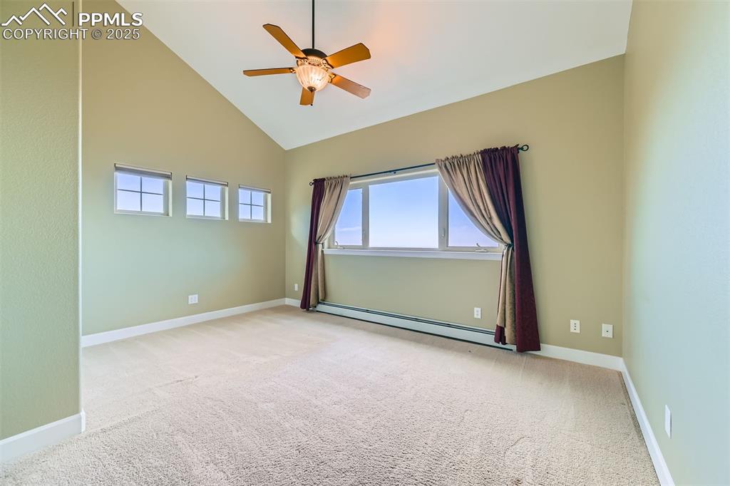 Image 18 of 27: Bedroom featuring baseboard heating, carpet, ceiling fan, expansive city an