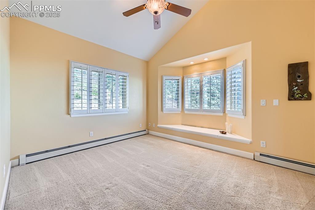 Image 19 of 27: Carpeted bedroom with a window seat, custom blinds, a ceiling fan, and high