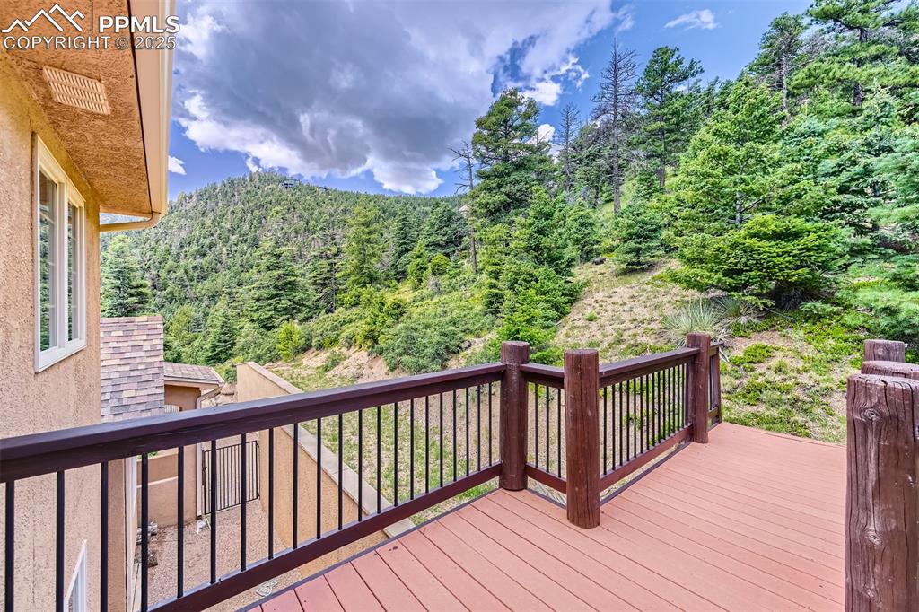 Image 22 of 27: Wooden terrace featuring a view of trees