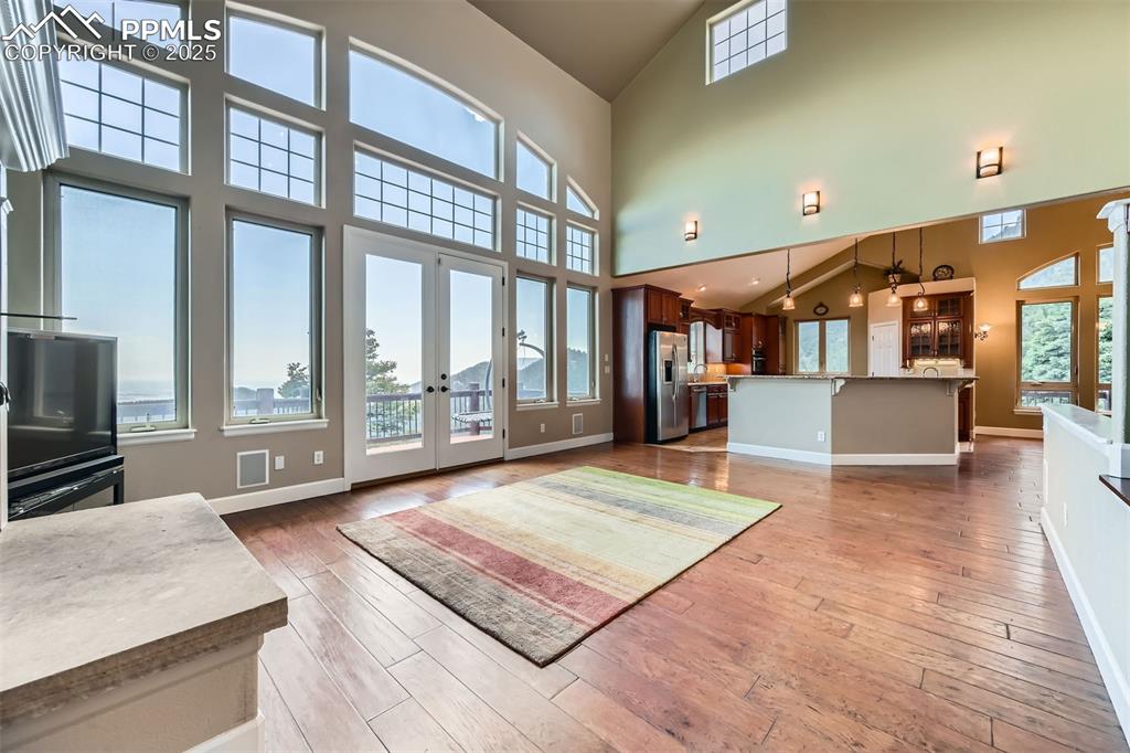 Image 7 of 27: Unfurnished living room featuring high vaulted ceiling, French doors, and w
