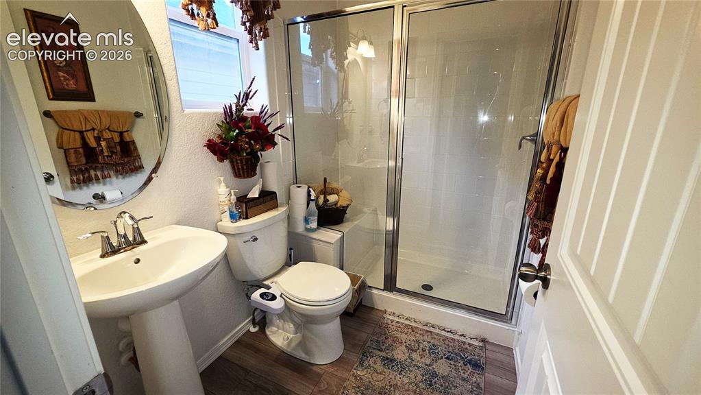 Image 32 of 48: Pedestal sink with chrome faucet, oval mirror, wood-finish flooring, and a