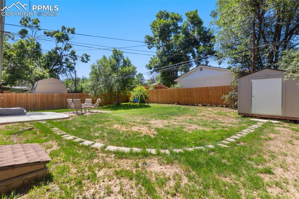 Image 24 of 31: Fenced backyard with a patio and a storage shed