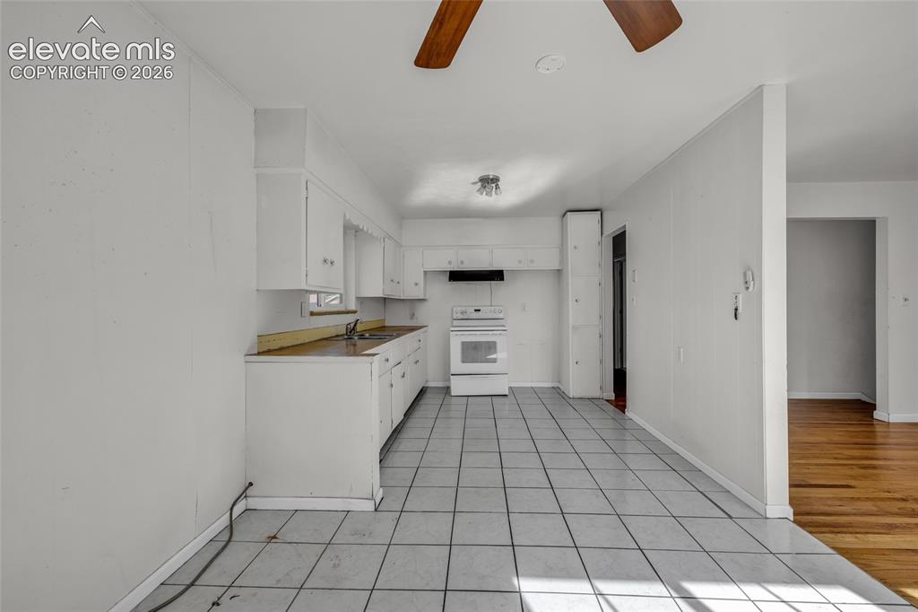 Image 10 of 25: Kitchen with white cabinetry, tile flooring, and a ceiling fan
