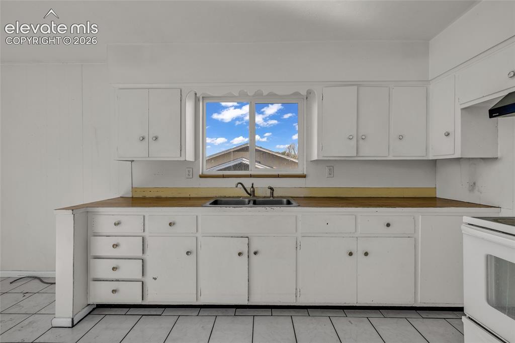 Image 11 of 25: White cabinetry featuring ample storage, a stainless steel double basin sin