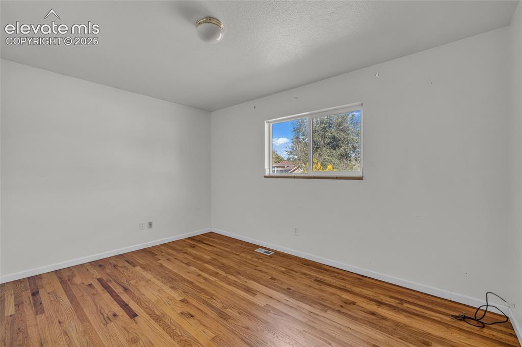 Image 14 of 25: Wood-finish flooring, white walls, and a ceiling-mounted light fixture