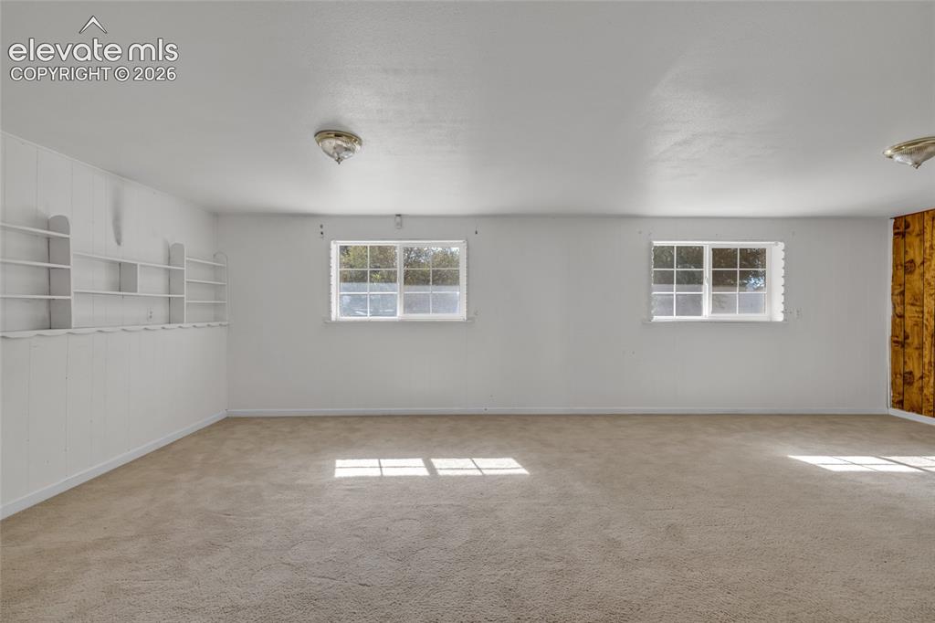 Image 17 of 25: Carpeted flooring with built-in shelving, white paneled wall, and dual wind
